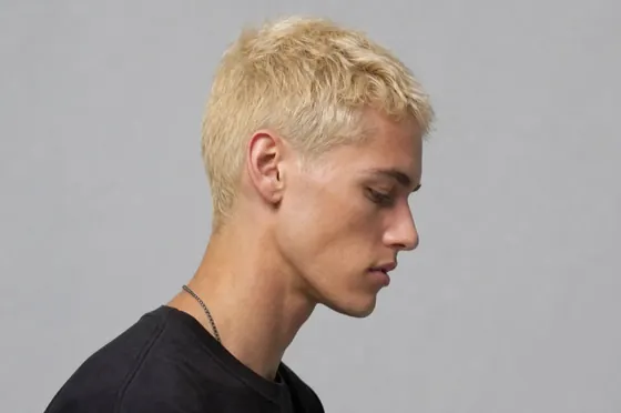 A studio photograph of a person in profile against a grey background